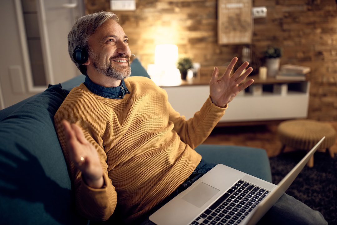 Homme à domicile utilisant un ordinateur portable avec casque, illustrant un check-up informatique annuel.