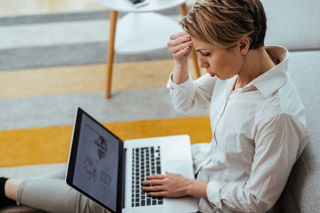 Femme stressée assise par terre devant son ordinateur portable à cause d'une panne d'Internet.